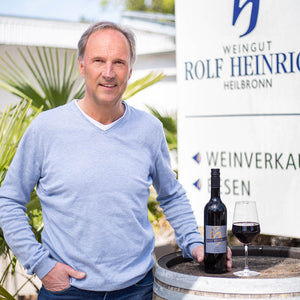 Andreas Heinrich steht an einem Weinfass und präsentiert den Merlot 