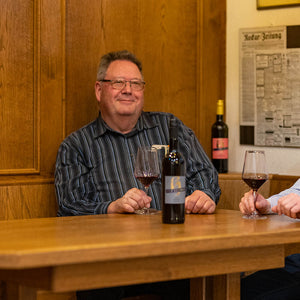 Thomas Heinrich sitzt am Tisch und genießt ein Glas Rotwein